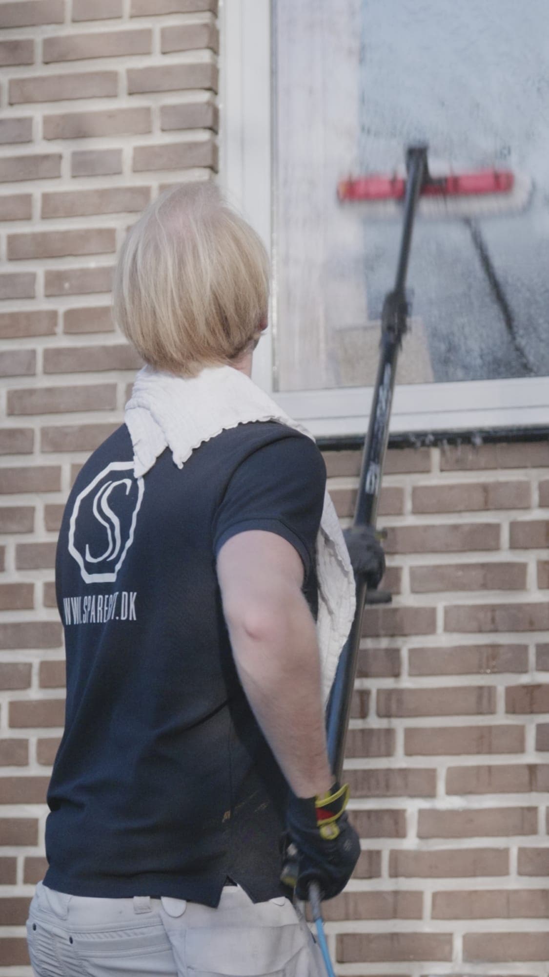 Sparegodt medarbejder bruger vaskeanlæg på vindue